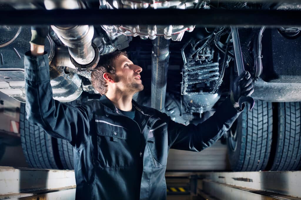 WB BAuer Werkstattservice. Mechaniker unter LKW auf Hebebühne.