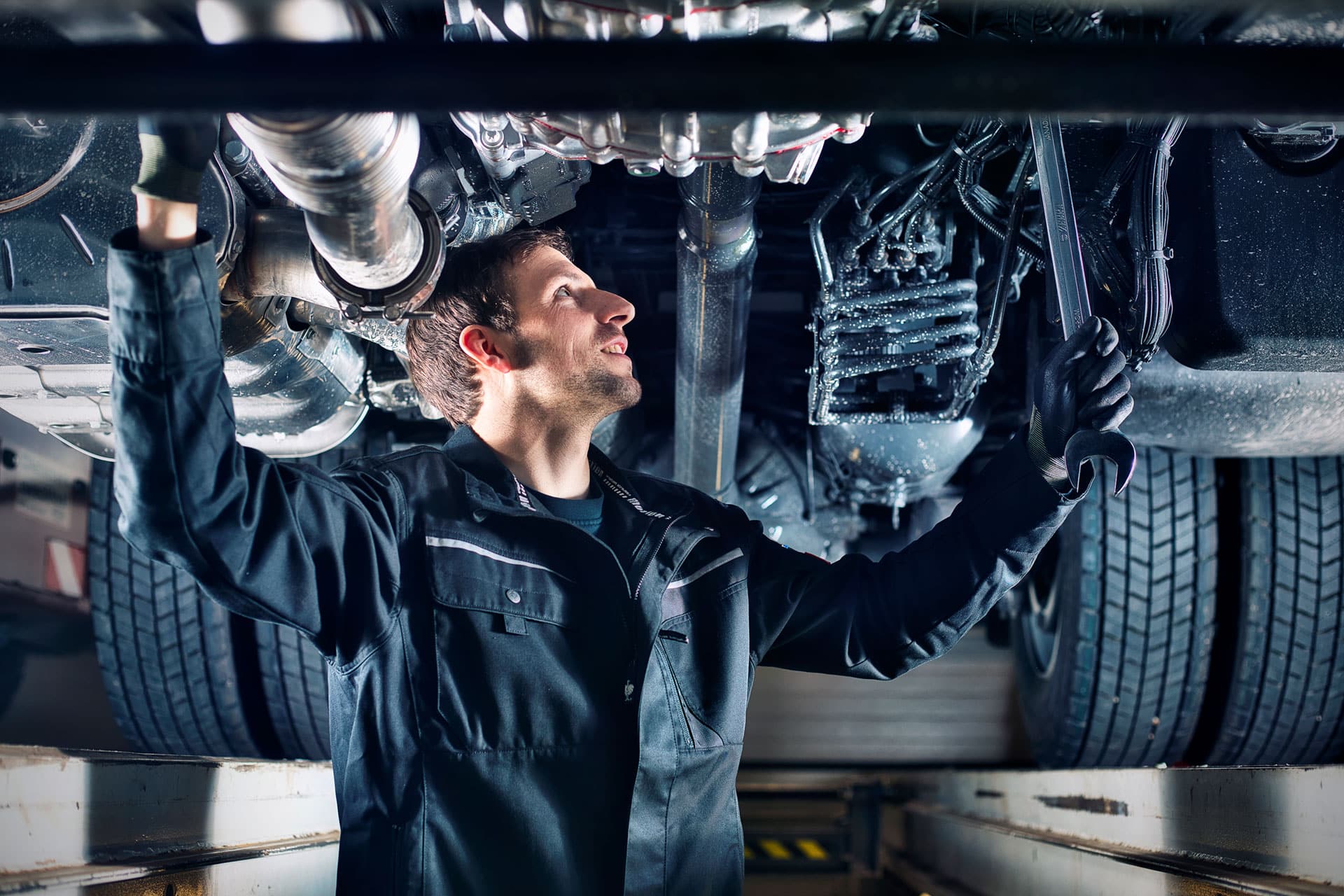 WB BAuer Werkstattservice. Mechaniker unter LKW auf Hebebühne.